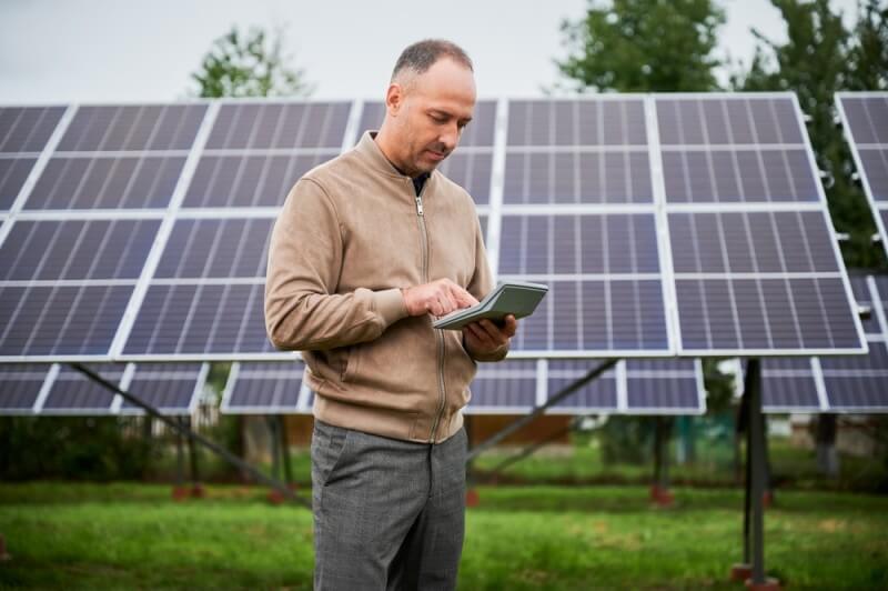 barbat analizand date langa panouri fotovoltaice