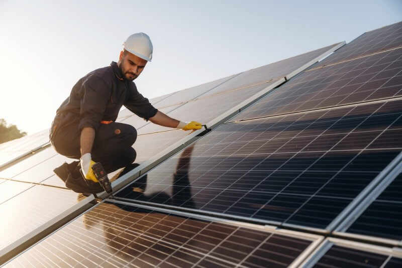 Reducerea emisiilor de CO2 în sectorul industrial: beneficiile energiei solare și stocării energiei 3 barbat montand panouri solare pe acoperisul unei fabrici industriale